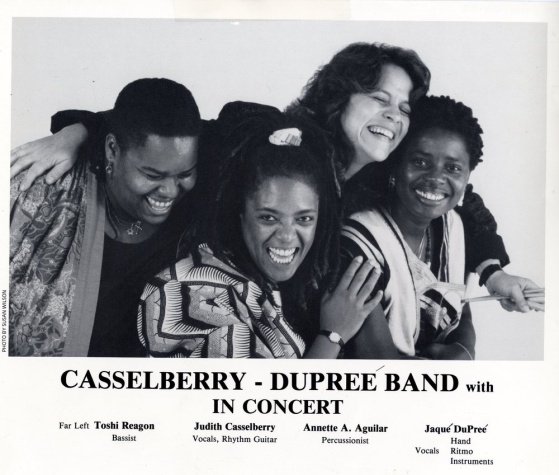 A promotional photo of members of the band Casselberry-Dupree laughing. Left-Right: Toshi Reagon bassist, Judith Casselberry vocals, rhythm guitar, Annette A. Aguilar percussionist, Jaque DuPree vocals, hand ritmo instruments. (Photograph by Susan Wilson)