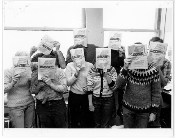 GCN members covering their face with "Subscribe" flyers. Back row (l-r): Mike Riegle, Richard Burns, Nancy Wechsler, and David Morris. Front row (l-r): Lisa Hershkop, Chris Gilfoy, Sue Hyde, Cindy Patton, and Larry Goldsmith. From Mike Riegle collection. Photo by Susan Fleischmann, 1984.
