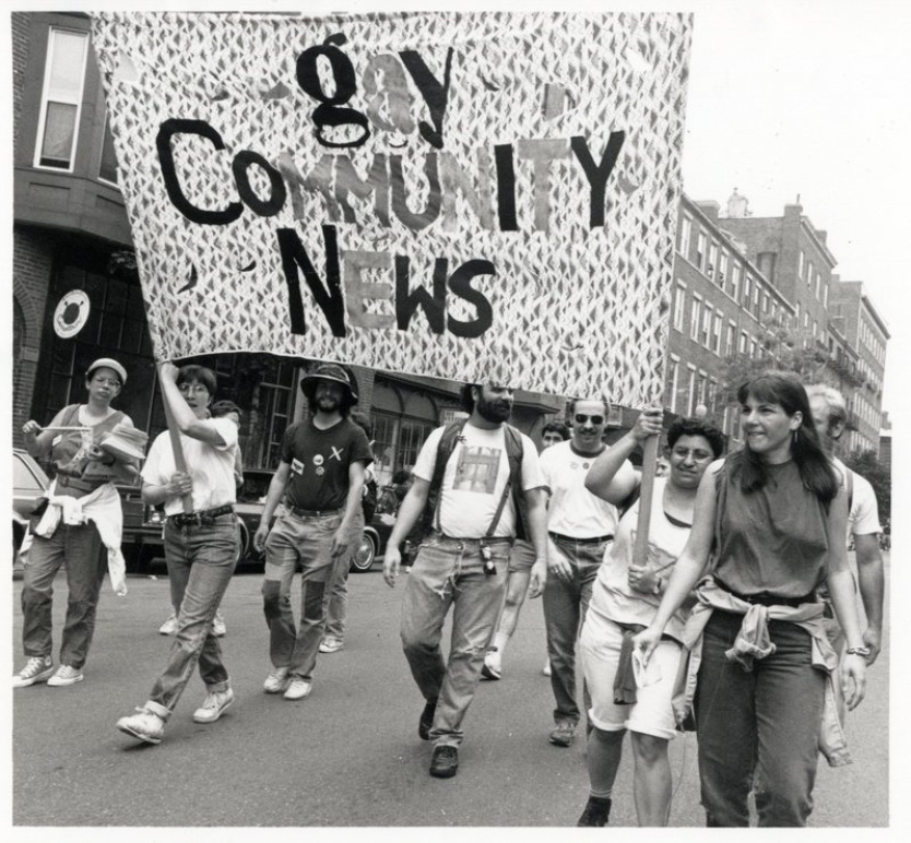 Photograph: Men and women of Gay Community News holding a large banner in the 1990 Pride march in Boston. Susan Fleischmann, Gay Community News Photograph Collection. 